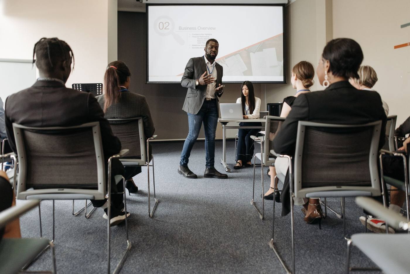 Business presenter speaking to a seated audience in a meeting room